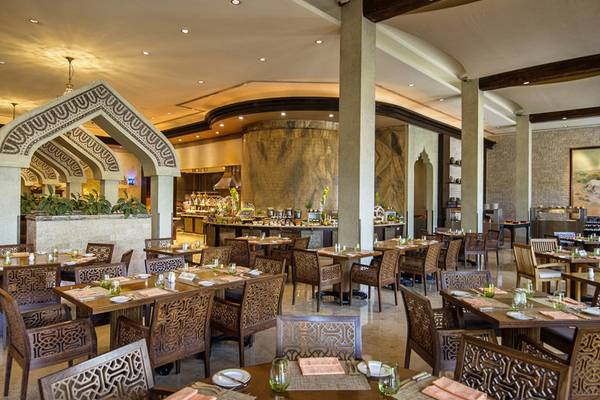 Innenansicht des Restaurants im Sharq Village und Spa, A Ritz Carlton Hotel mit gedeckten Tischen und Stühlen.
