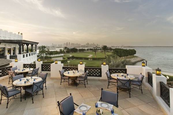 Außenterrasse des Sharq Village und Spa Hotels mit Blick auf einen Golfplatz und das Meer