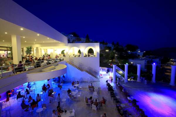 Außenbereich des Larissa Bodrum View Resorts bei Nacht mit blauen Lichtern und Gästen an Tischen.