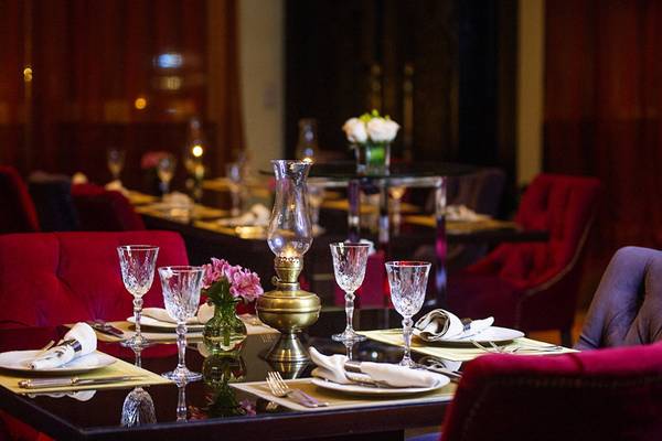 Sitzbereich im Sharq Village und Spa, Ritz Carlton Hotel, mit Tisch, roter Stuhl und Tischdekoration.