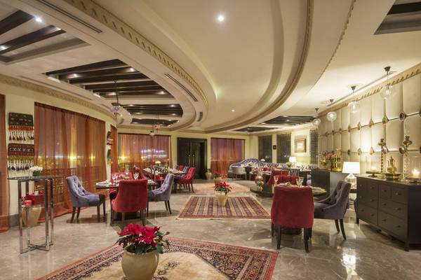 Innenbereich des Sharq Village and Spa, A Ritz Carlton Hotel mit runden Tischen, Stühlen und Blumendekoration.