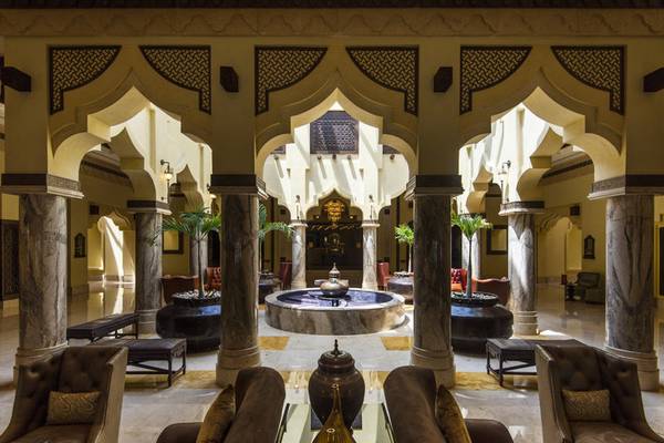 Lobby des Sharq Village and Spa, A Ritz Carlton Hotel mit Brunnen, Säulen und Möbeln.