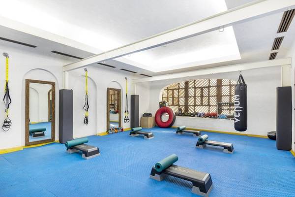 Fitnessraum im Sharq Village and Spa mit blauem Boden und Trainingsgeräten.