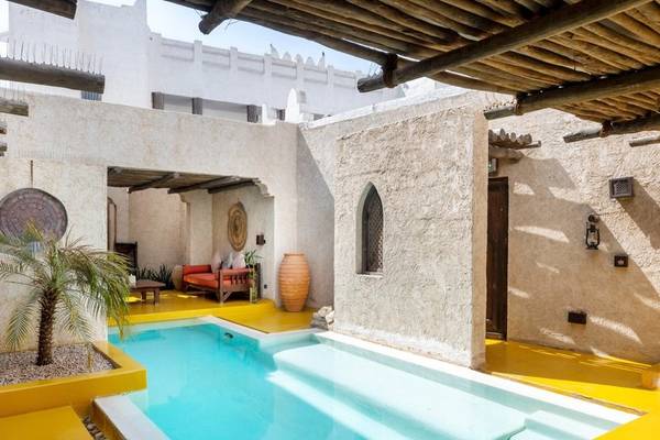 Schwimmbeckenbereich im Sharq Village und Spa Hotel mit gelben Wänden und einem roten Sofa.