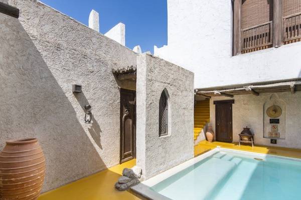 Außenbereich des Sharq Village und Spa mit einem Pool und einer gelben Bodenfläche.