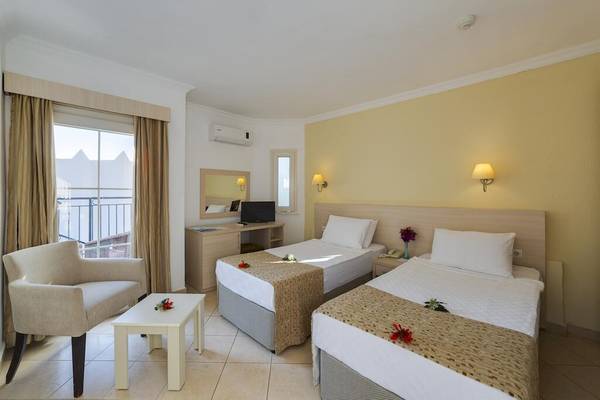 Doppelzimmer im Larissa Bodrum View Resort mit zwei Betten, einem Tisch und einem Stuhl.