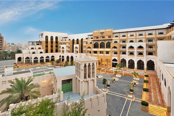 Außenansicht des Al Najada Doha Hotel by Tivoli mit vielen Gebäuden und Palmen