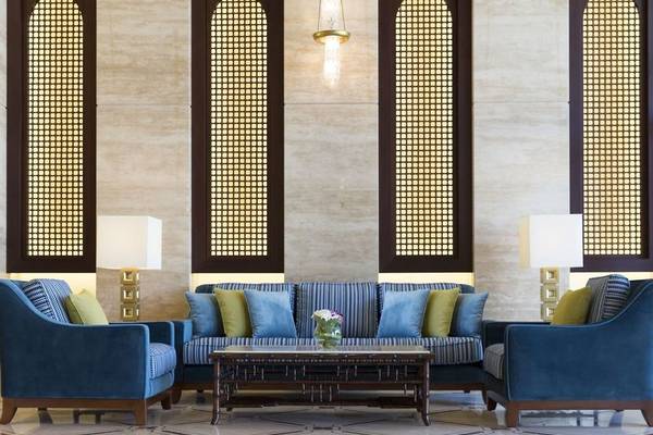 Lobby des Al Najada Doha Hotel by Tivoli mit blauen Sofas und leuchtenden Deckenlampen.