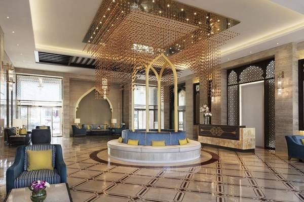Empfangsbereich des Al Najada Doha Hotel by Tivoli mit blauen Möbeln und goldener Beleuchtung.