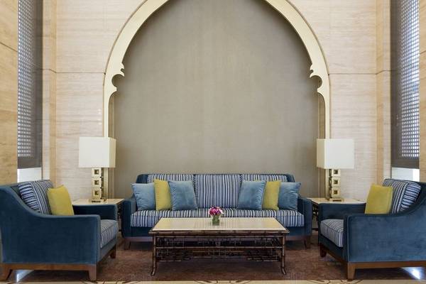 Lobby-Lounge des Al Najada Doha Hotel by Tivoli mit blauen Sofas und Tisch.