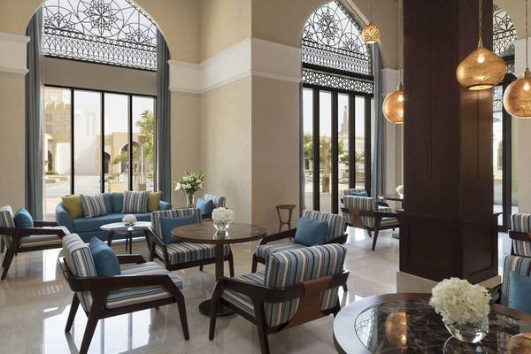 Loungebereich des Al Najada Doha Hotel by Tivoli mit gemusterten Stühlen und Tischen.