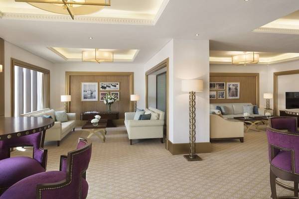 Lobby-Bereich des Al Najada Doha Hotel by Tivoli mit weißen Möbeln und goldenen Lampen.
