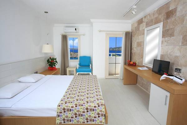 Innenansicht eines Hotelzimmers im Larissa Bodrum View Resort mit Bett, Fenstern und Meerblick.