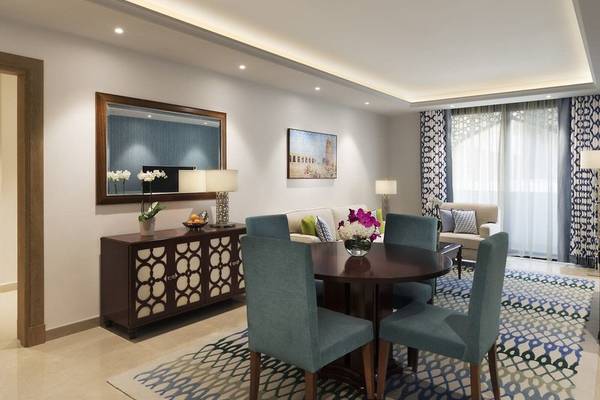 Innenraum einer Suite im Al Najada Doha Hotel by Tivoli mit Esstisch, Sofa und Dekor.