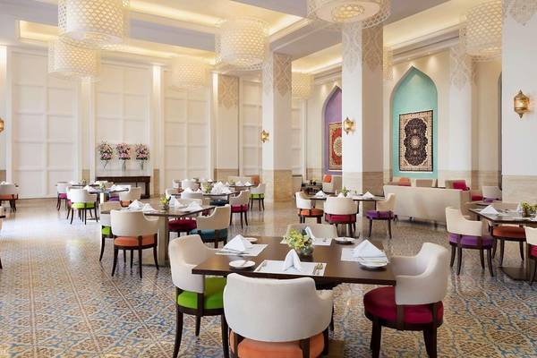 Innenansicht des Restaurants im Al Najada Doha Hotel by Tivoli mit farbenfrohen Stühlen und Tischen.