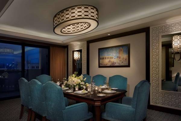 Elegantes Esszimmer im Al Najada Doha Hotel by Tivoli mit blauen Stühlen und Tisch.