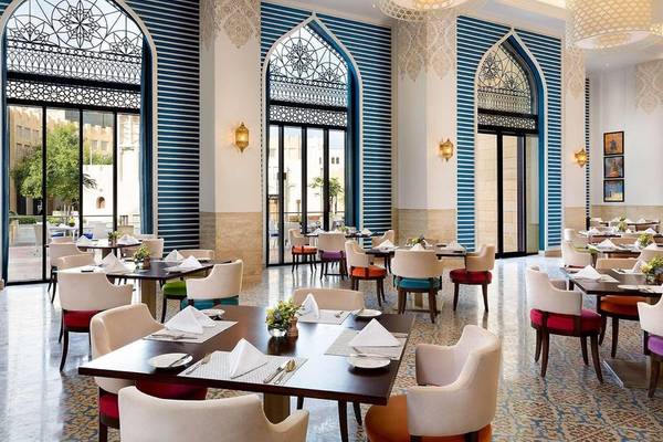 Innenansicht des Restaurants im Al Najada Doha Hotel by Tivoli mit blau-weiß gestreiften Wänden und runden Fenstern.