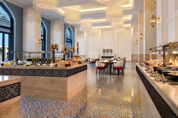 Innenansicht des Al Najada Doha Hotel by Tivoli Restaurants mit Buffet und Tischen.