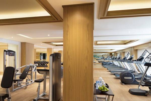 Fitnessstudio im Al Najada Doha Hotel by Tivoli mit vielen Geräten und einer langen Reihe von Laufbändern.