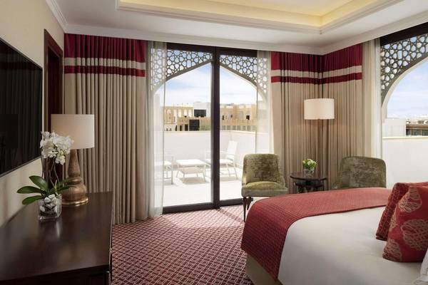 Innenansicht eines Zimmers im Al Najada Doha Hotel by Tivoli mit Bett, Balkon und Aussicht auf die Stadt.