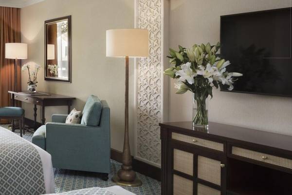 Innenansicht der Suite im Al Najada Doha Hotel by Tivoli mit Möbeln, Fernseher und Blumenvase.