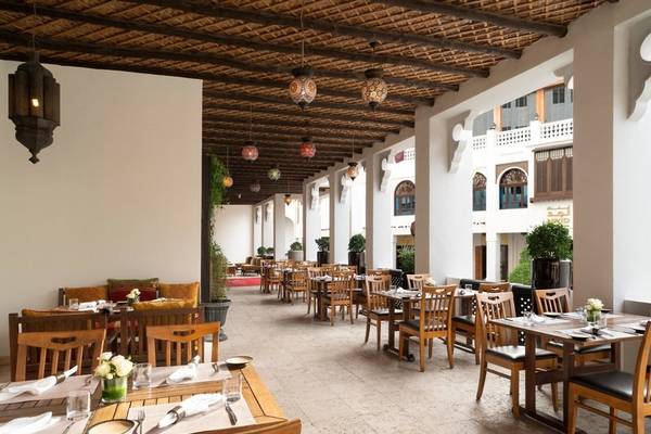 Innenbereich des Restaurants im Souq Waqif Boutique Hotels mit Tisch und Stühlen, Deckenleuchten und Pflanzen.