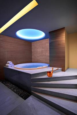 Jacuzzi-Raum im Souq Waqif Boutique Hotels mit blauer Beleuchtung und Holzwänden.
