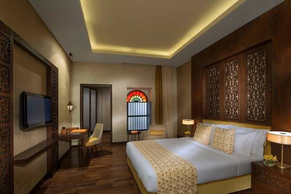 Souq Waqif Boutique Hotels Schlafzimmer mit Bett, Fernseher, Schreibtisch und Fenstern
