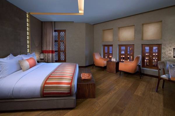 Schlafzimmer im Souq Waqif Boutique Hotels mit einem großen Bett und drei Sesseln.