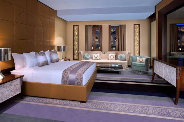 Suite-Zimmer im Souq Waqif Boutique Hotels mit einem großen Bett und einem Wohnzimmerbereich.