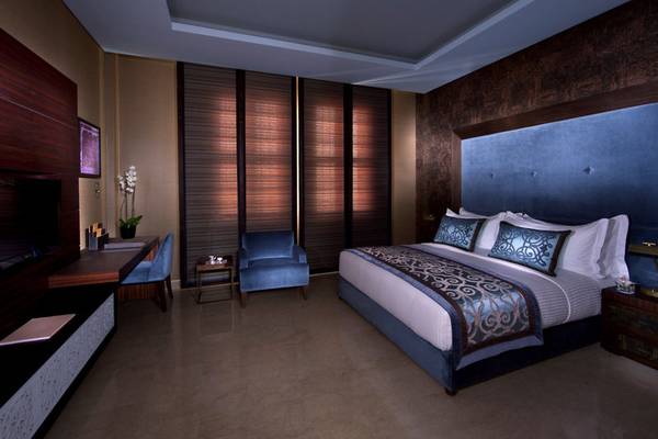 Schlafzimmer im Souq Waqif Boutique Hotels mit Bett, Sesseln und Fernseher.