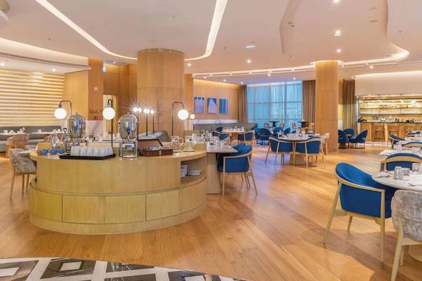 Innenansicht des Restaurants im Embassy Suites By Hilton Doha Old Town mit Holzboden und blauen Stühlen.