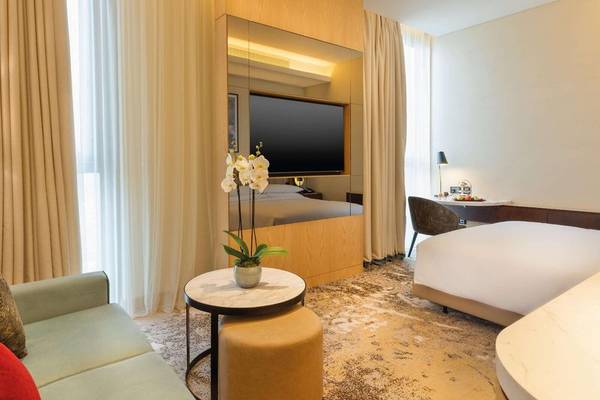 Hotelzimmer des Embassy Suites By Hilton Doha Old Town mit Bett, Fernseher, Tisch und Fenster.