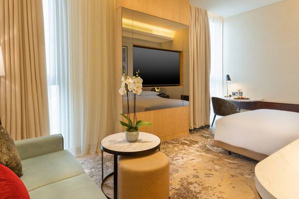 Innenansicht der Suite im Embassy Suites By Hilton Doha Old Town mit Sofa, Tisch, Fernseher und Bett.