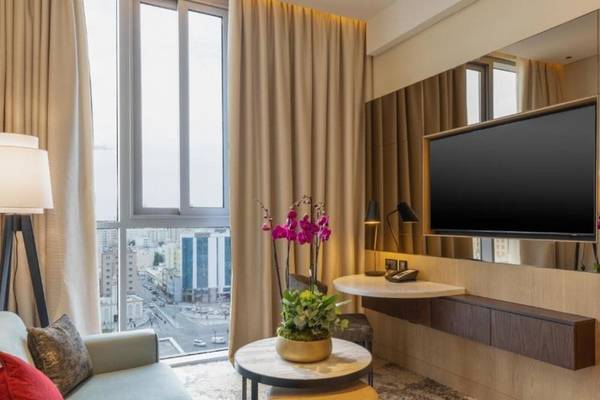 Innenraum des Embassy Suites By Hilton Doha Old Town Hotel mit Sofa, Tisch und Fernseher.
