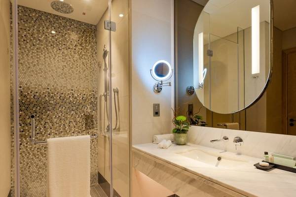 Badezimmer im Embassy Suites By Hilton Doha Old Town mit Glasdusche und Waschbecken.