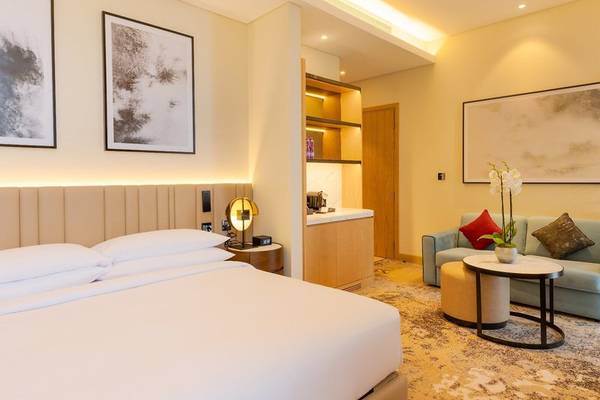 Schlafzimmer im Embassy Suites By Hilton Doha Old Town mit großem Bett, Couch, Tisch und Kunstwerken an der Wand.