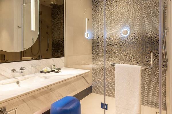Badezimmer im Embassy Suites By Hilton Doha Old Town mit Marmorfliesen und Duschbereich.