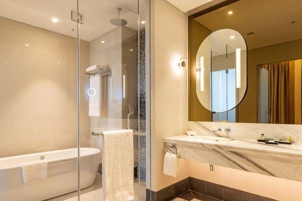 Badezimmer im Embassy Suites By Hilton Doha Old Town mit Badewanne, Dusche, Spiegel und Waschbecken.
