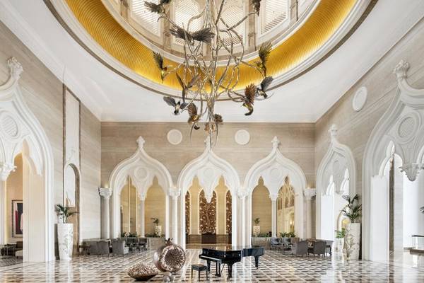 Lobby des Marsa Malaz Kempinski, The Pearl Hotel mit Marmorboden, zentralem Kronleuchter und Klavier.