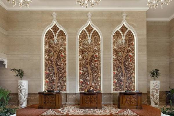 Rezeption des Marsa Malaz Kempinski, The Pearl mit drei großen Wandgemälden und drei Empfangstischen.