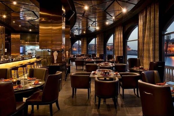 Innenansicht des Marsa Malaz Kempinski, The Pearl Restaurants mit runden Tischen und Stühlen.