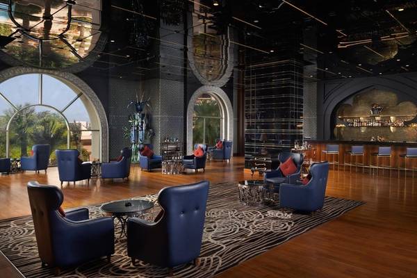 Innenansicht der Lobby des Marsa Malaz Kempinski Hotels mit blauen Sesseln, Holzboden und zentralem Teppich.