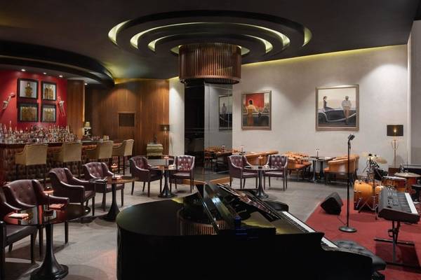 Loungebereich im Marsa Malaz Kempinski, The Pearl Hotel mit Klavier, Bar und gepolsterten Stühlen.