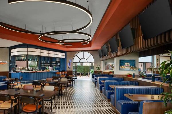 Innenansicht des Marsa Malaz Kempinski, The Pearl Restaurants mit blauen Bänken und Tischen, einer Theke und dekorativen Leuchten.