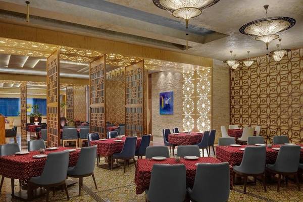 Innenansicht des Marsa Malaz Kempinski Restaurants mit Tisch und Stühlen, gemusterte Wände und Deckenlampen.