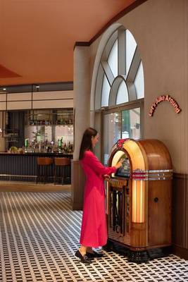 Eine Frau in einem roten Kleid spielt an einem Jukebox-Automaten im Marsa Malaz Kempinski Hotel.
