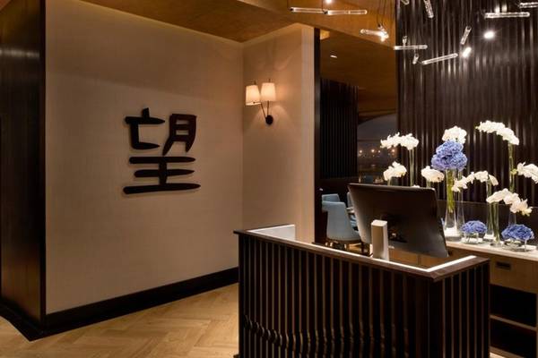 Empfangsbereich des Marsa Malaz Kempinski mit chinesischem Zeichen an der Wand, Blumenarrangements und Schreibtisch.