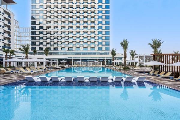 Rixos Gulf Hotel Doha mit großem Swimmingpool und Liegestühlen unter Sonnenschirmen
