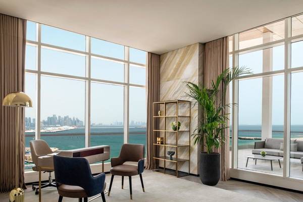 Innenraum des Rixos Gulf Hotel Doha mit Blick auf das Meer, Möbel und Pflanzen.